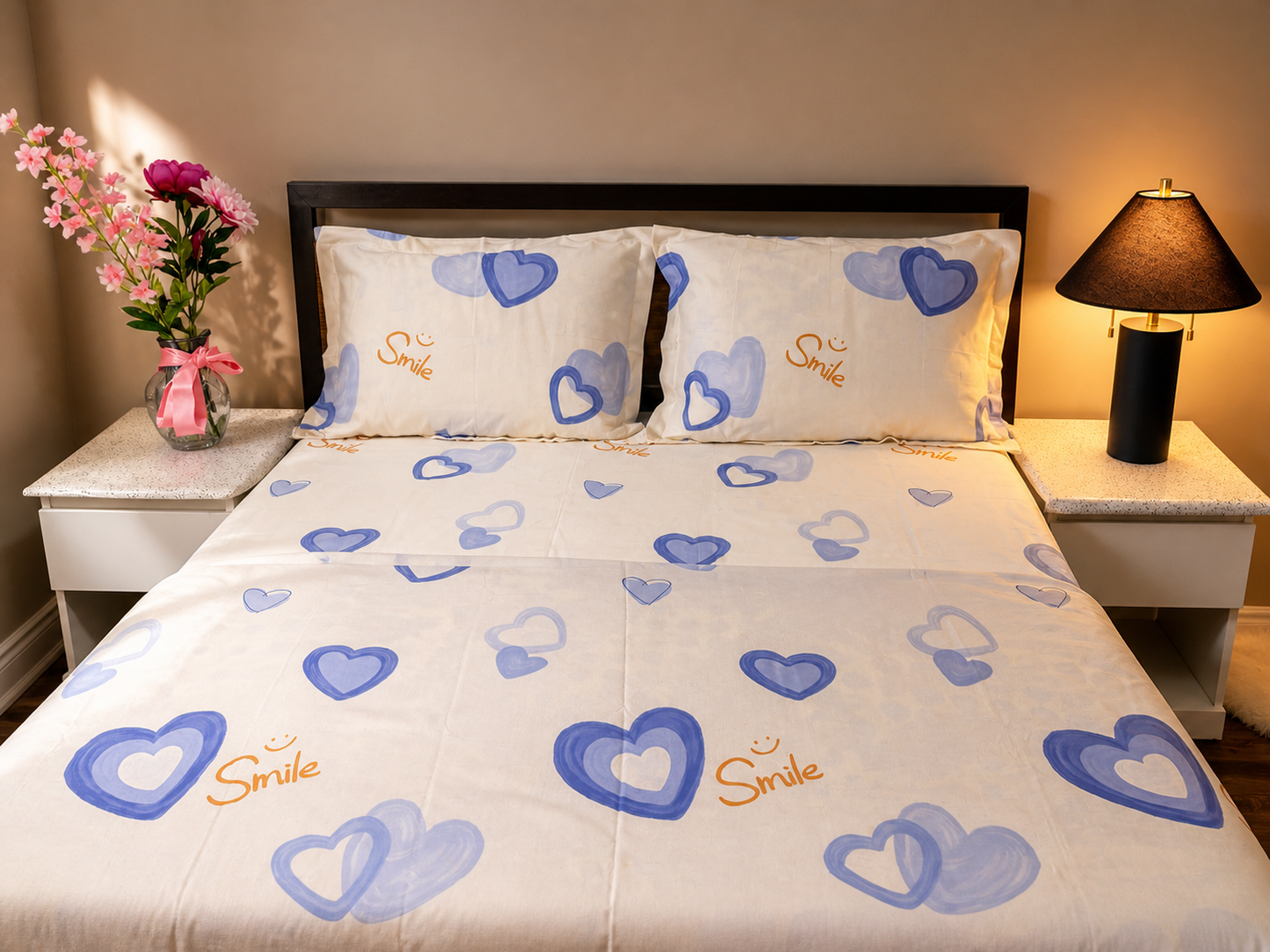 Bed with heart-patterned bedding and matching pillows in a bedroom setting.