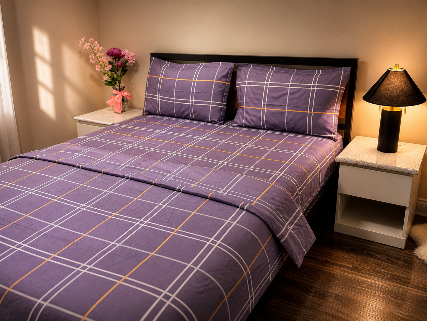 Bed with purple plaid bedding in a bedroom setting with nightstands and a lamp.
