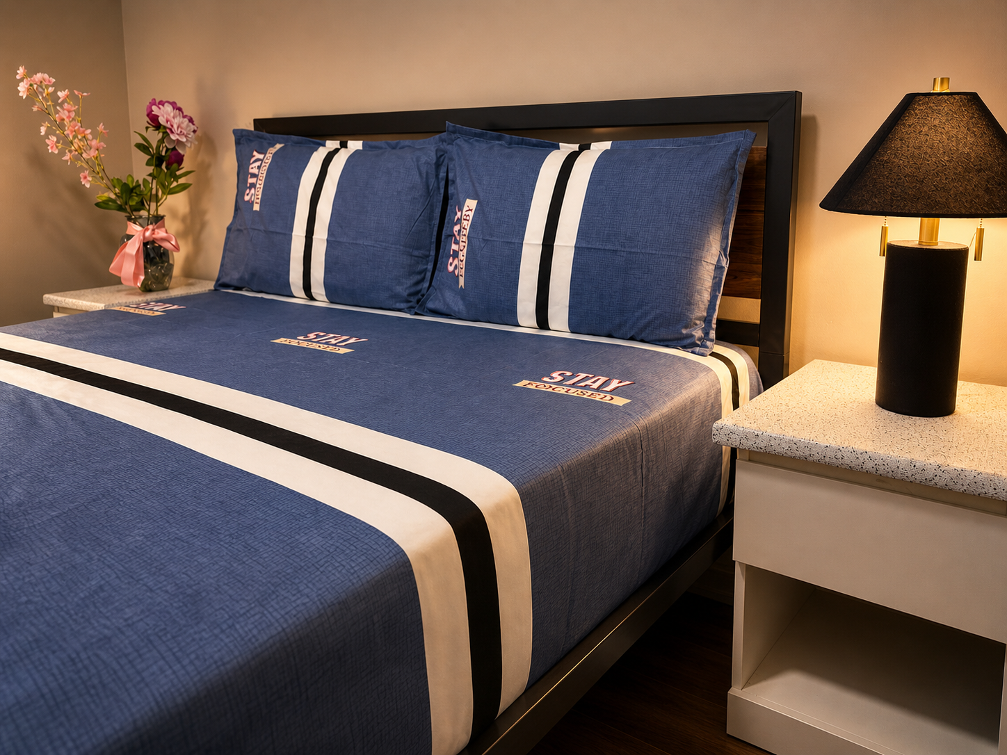 Blue bedspread with white and black stripes on a bed in a bedroom setting.